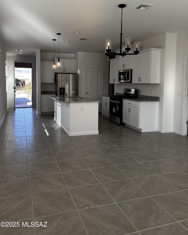 kitchen featuring decorative light fixtures, a center island with sink, white cabinets, and appliances with stainless steel finishes