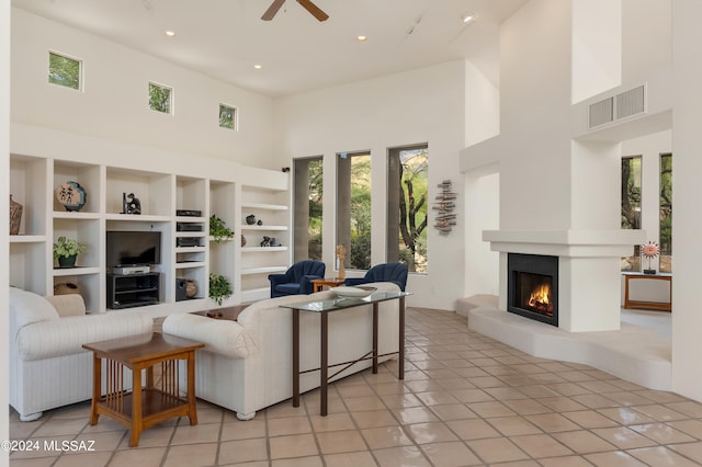 living room with ceiling fan, light tile patterned floors, and a high ceiling