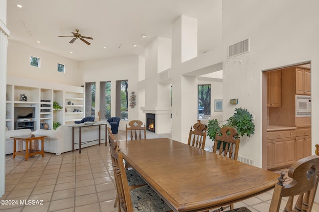 tiled dining room featuring ceiling fan, a towering ceiling, and built in features