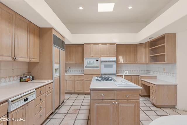 kitchen with decorative backsplash, light tile patterned flooring, a kitchen island, built in appliances, and sink