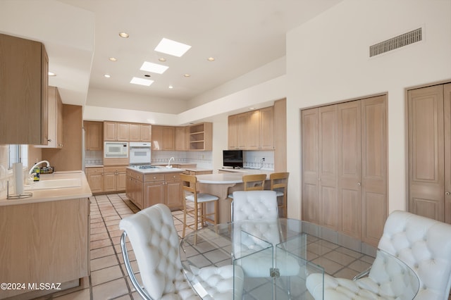 tiled dining room with sink and a skylight