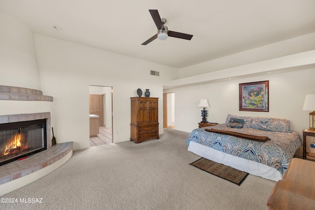 bedroom featuring ceiling fan, light colored carpet, a fireplace, and connected bathroom