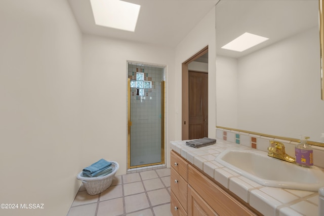 bathroom with vanity, a skylight, a shower with shower door, and tile patterned flooring