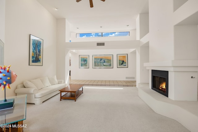 carpeted living room with a high ceiling and ceiling fan