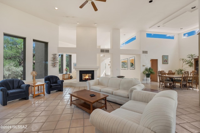 living room with ceiling fan, a towering ceiling, and light tile patterned floors