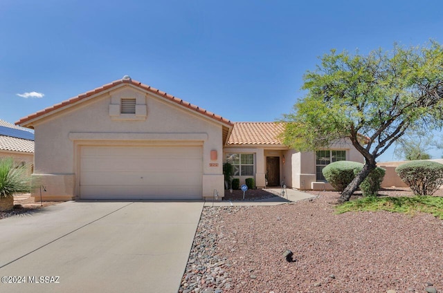 mediterranean / spanish-style home featuring concrete driveway, a tiled roof, an attached garage, and stucco siding