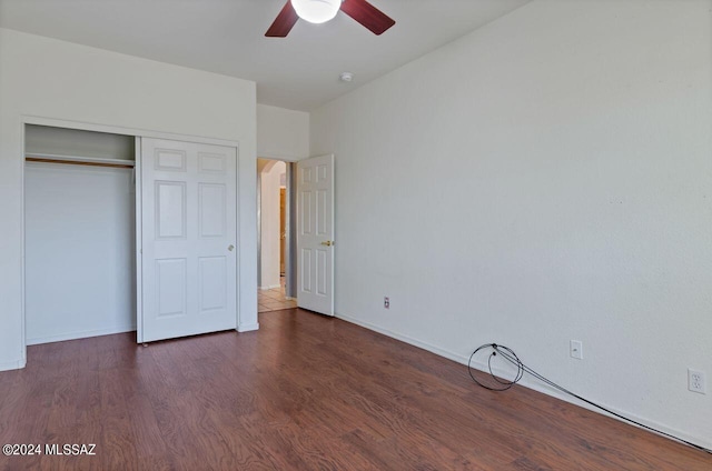 unfurnished bedroom with baseboards, ceiling fan, arched walkways, a closet, and dark wood-style flooring