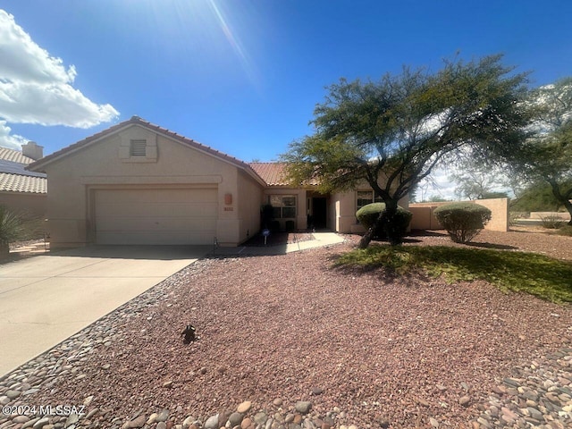 view of front of home with a tiled roof, stucco siding, driveway, and a garage