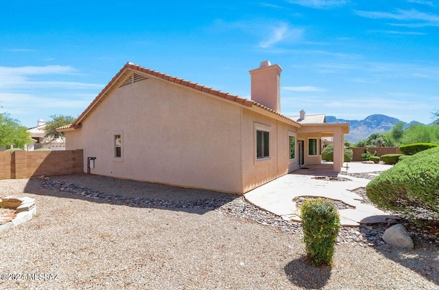 back of house featuring stucco siding, a patio, a chimney, and fence