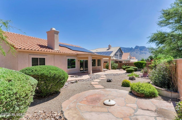 rear view of house featuring stucco siding, a tile roof, a fenced backyard, a chimney, and a patio area