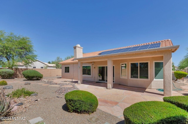 rear view of property featuring a patio area, fence, a chimney, and a tile roof