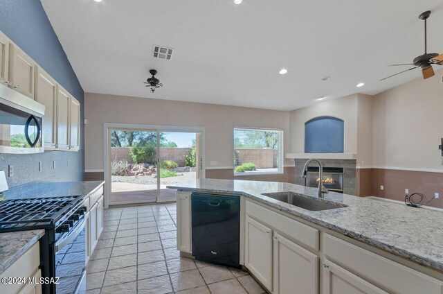 kitchen with ceiling fan, sink, a tiled fireplace, stainless steel appliances, and vaulted ceiling