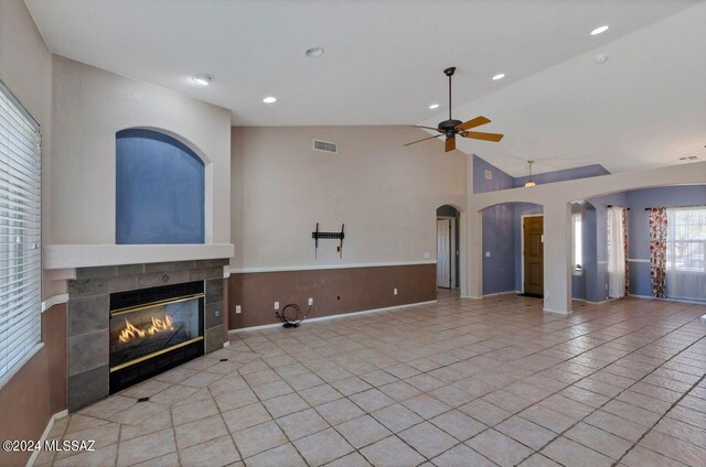 tiled living room with high vaulted ceiling, ceiling fan, and a fireplace