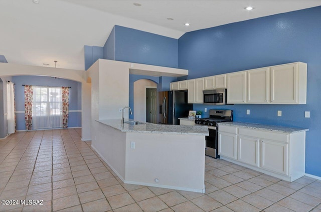 kitchen with a sink, high vaulted ceiling, white cabinetry, and stainless steel appliances