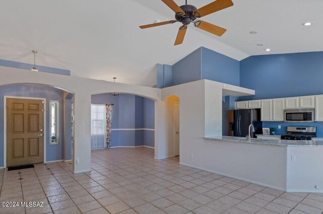 kitchen featuring high vaulted ceiling, light stone countertops, light tile patterned floors, stainless steel appliances, and ceiling fan