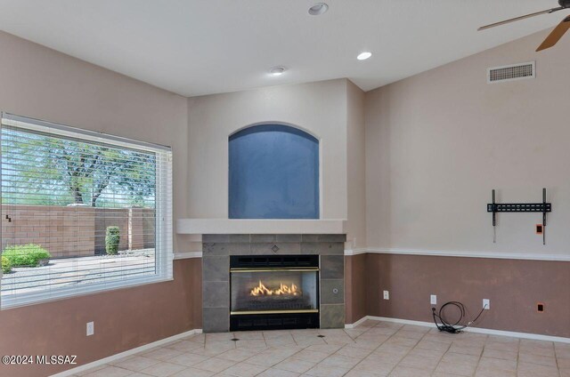 unfurnished living room featuring a tiled fireplace, ceiling fan, vaulted ceiling, and light tile patterned floors