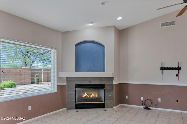 unfurnished living room with visible vents, a ceiling fan, a tiled fireplace, tile patterned flooring, and baseboards