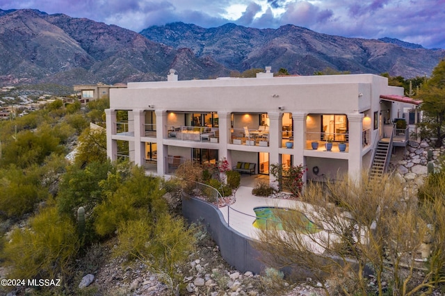 back house at dusk with a balcony and a mountain view