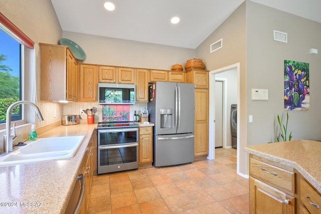 kitchen with washer / clothes dryer, backsplash, light tile patterned floors, sink, and stainless steel appliances