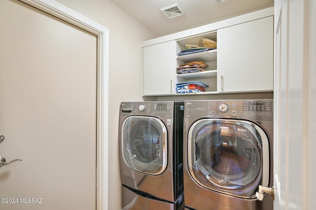 clothes washing area with cabinets and independent washer and dryer