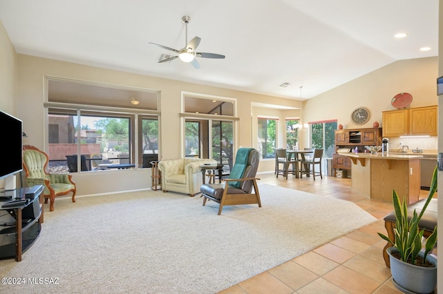 living room with ceiling fan, vaulted ceiling, light tile patterned floors, and plenty of natural light