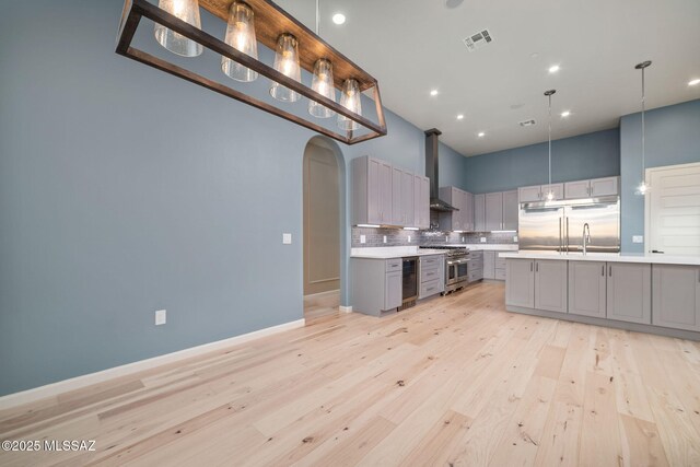 kitchen featuring premium appliances, decorative light fixtures, light hardwood / wood-style floors, decorative backsplash, and gray cabinets