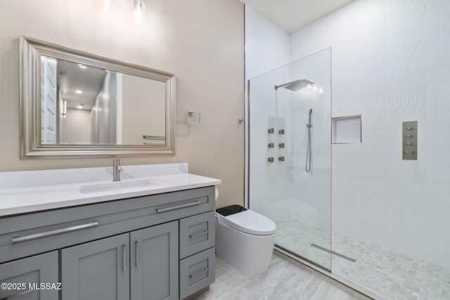 bathroom with vanity, tiled shower, and toilet