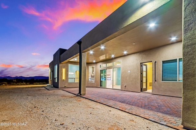 back house at dusk featuring a patio