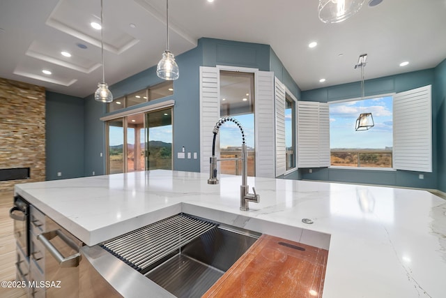 kitchen featuring blue cabinetry, pendant lighting, light stone countertops, and a wealth of natural light