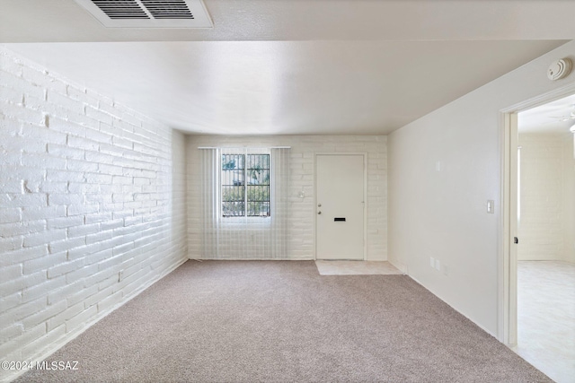 carpeted empty room with brick wall