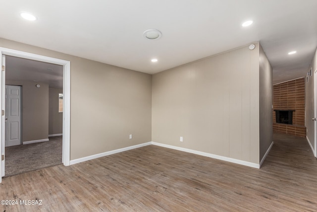 spare room with hardwood / wood-style floors and a brick fireplace