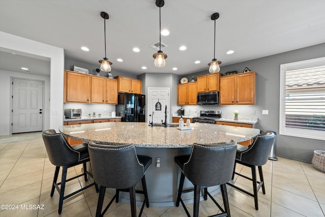 kitchen featuring decorative light fixtures, an island with sink, appliances with stainless steel finishes, and a kitchen bar