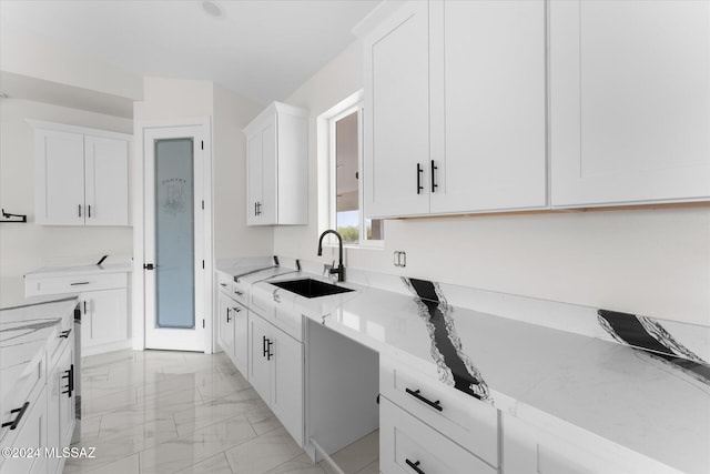 kitchen featuring white cabinetry, sink, and light stone counters