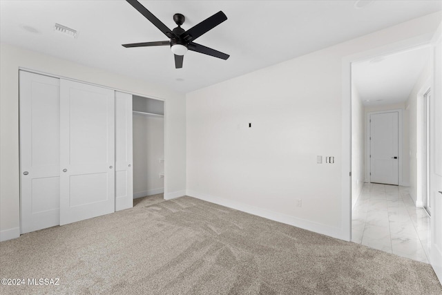 unfurnished bedroom with light colored carpet, ceiling fan, and a closet