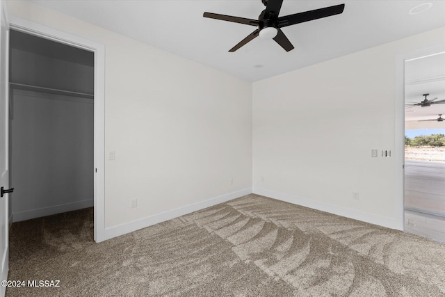 unfurnished bedroom with a closet, a spacious closet, carpet flooring, and ceiling fan