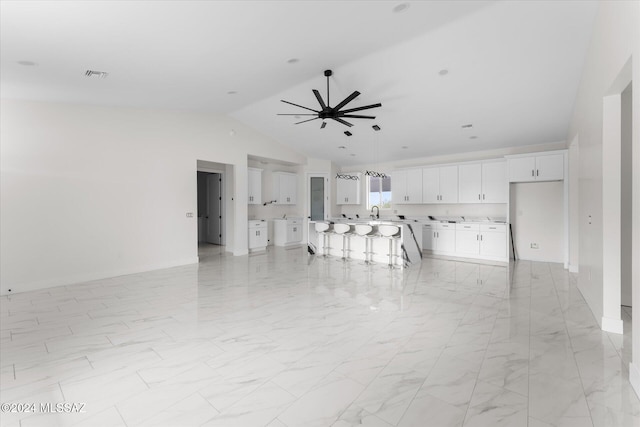 unfurnished dining area featuring ceiling fan, sink, and vaulted ceiling