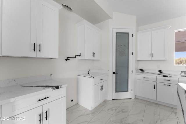 kitchen featuring light stone counters, ceiling fan, and white cabinets