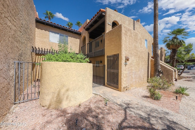 view of property exterior featuring a tile roof, a gate, fence, and stucco siding