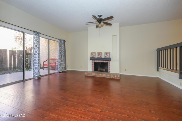 unfurnished living room featuring a textured ceiling, a brick fireplace, ceiling fan, and dark wood-type flooring