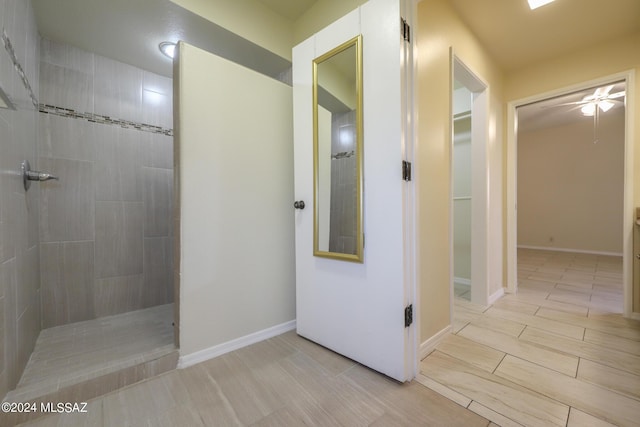 bathroom with a tile shower and ceiling fan