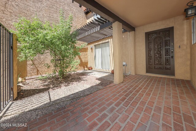 entrance to property featuring a pergola and a patio