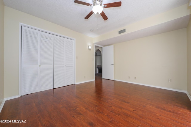 unfurnished bedroom with a textured ceiling, a closet, ceiling fan, and dark wood-type flooring