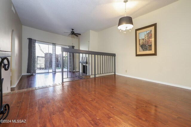 unfurnished living room featuring dark hardwood / wood-style flooring, a textured ceiling, and ceiling fan