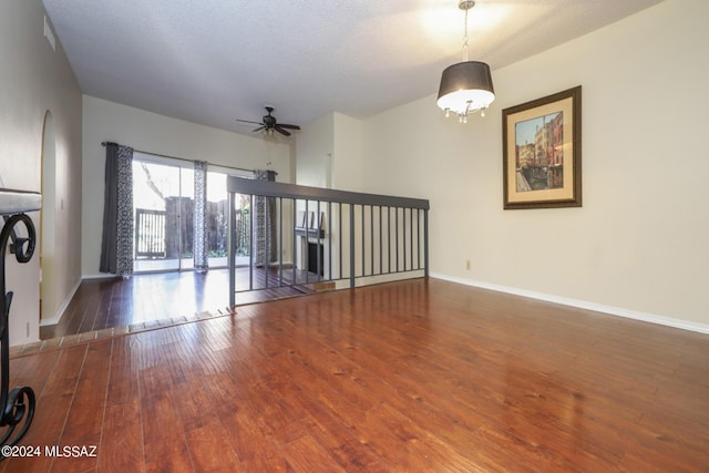 spare room with wood-type flooring, a ceiling fan, and baseboards