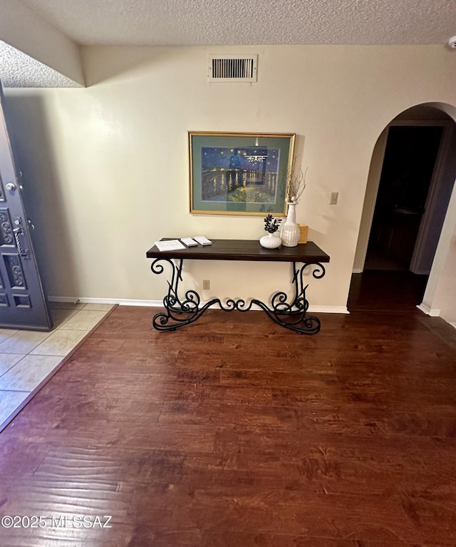 hall with wood-type flooring and a textured ceiling