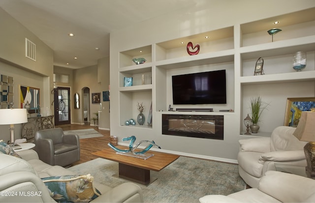 living area with recessed lighting, built in shelves, arched walkways, visible vents, and wood finished floors