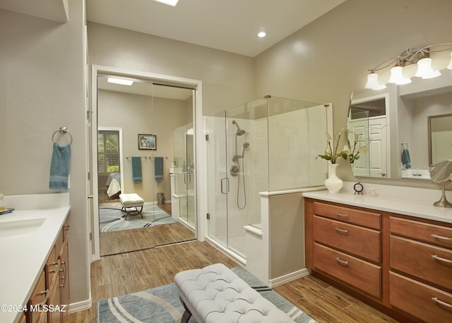 ensuite bathroom featuring vanity, a shower stall, wood finished floors, ensuite bathroom, and baseboards