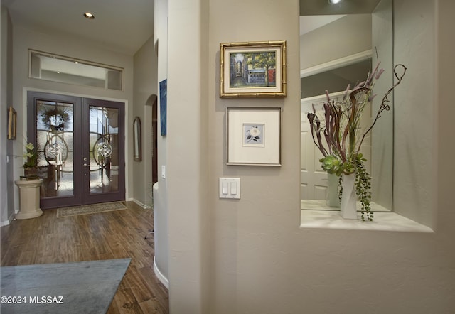 foyer entrance with baseboards, wood finished floors, arched walkways, and french doors