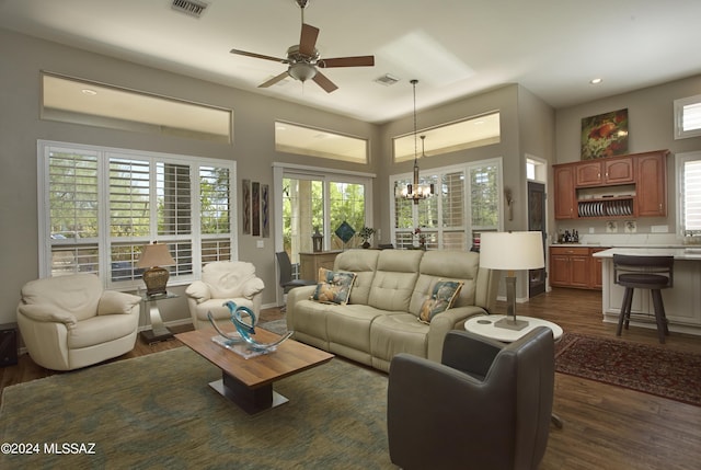 living room with dark wood-style floors, plenty of natural light, ceiling fan with notable chandelier, and visible vents