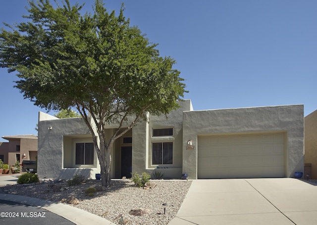 pueblo-style home featuring stucco siding, a garage, and concrete driveway